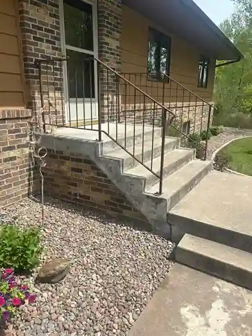Custom iron handrails on brick home entry stairs